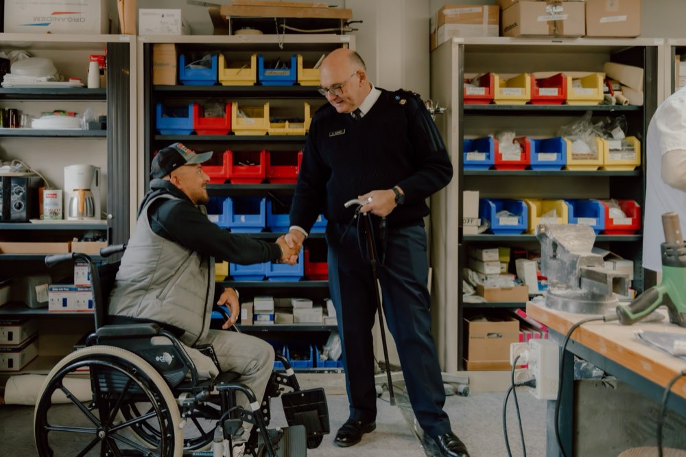 Un officier en uniforme salue un patient en fauteuil roulant d'une poignée de main, au centre d'appareillage de l'INI