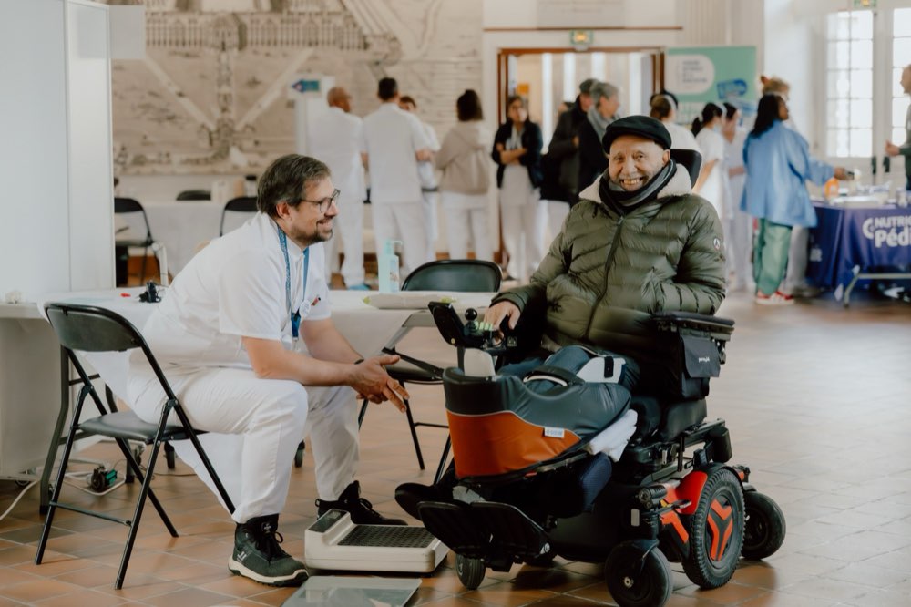 Un soignant échange en souriant avec un pensionnaire en fauteuil roulant
