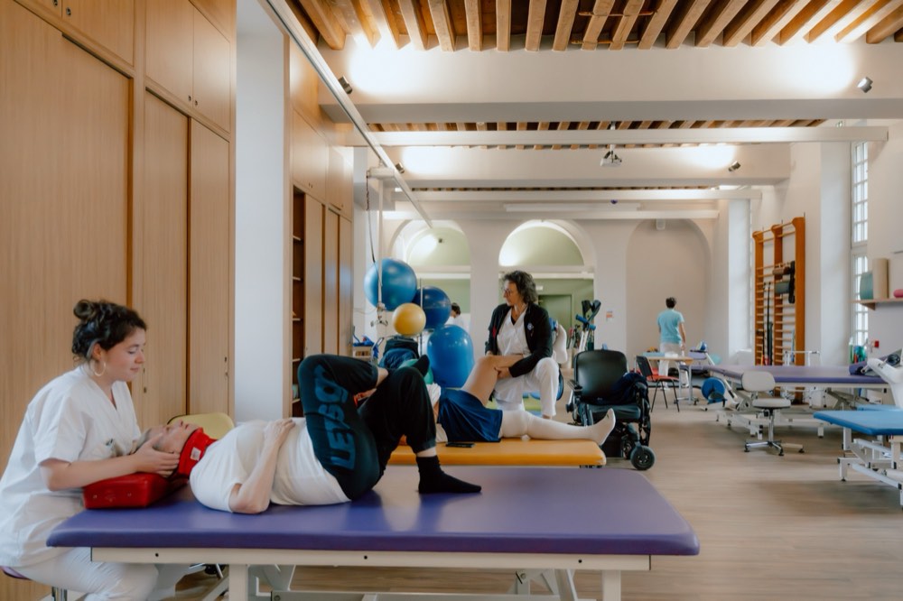 Séance de rééducation à l'INI : une kinésithérapeute accompagne un patient allongé dans la salle de réhabilitation