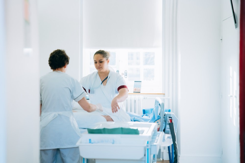 Deux soignantes prodiguent des soins à un patient alité dans une chambre de l'INI